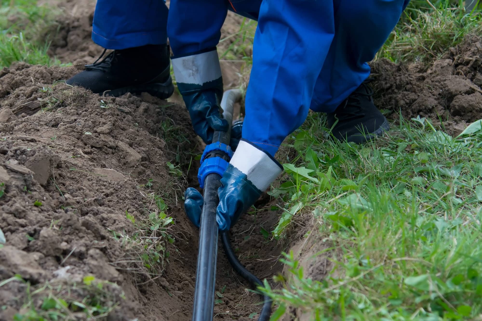A plumber installs new piping inside of a trench within the backyard of home in Leander, TX.