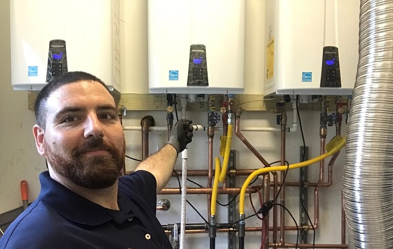 A licensed and experienced plumber showing the installation of 3 Navien tankless water heaters.